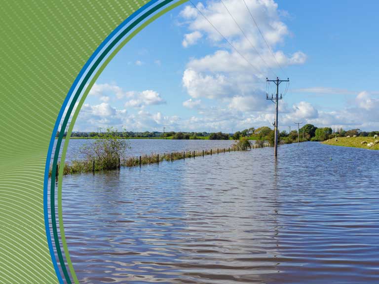Flooded rural landscape with power lines and water extending to the horizon, under a partly cloudy s.