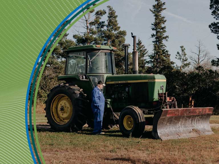 Tractor with worker on farmland promoting agricultural safety in Canada.