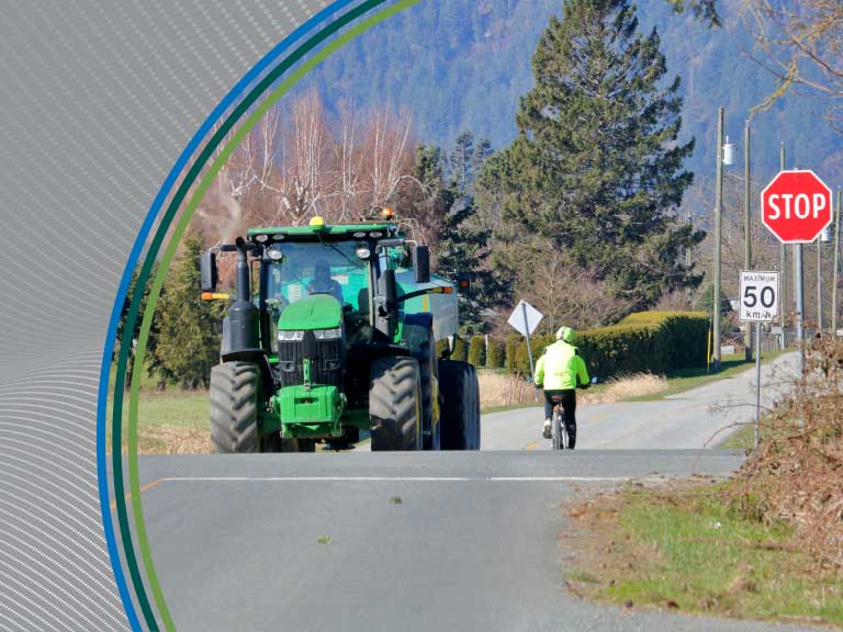 Tractor and cyclist on rural road with stop sign in the background.