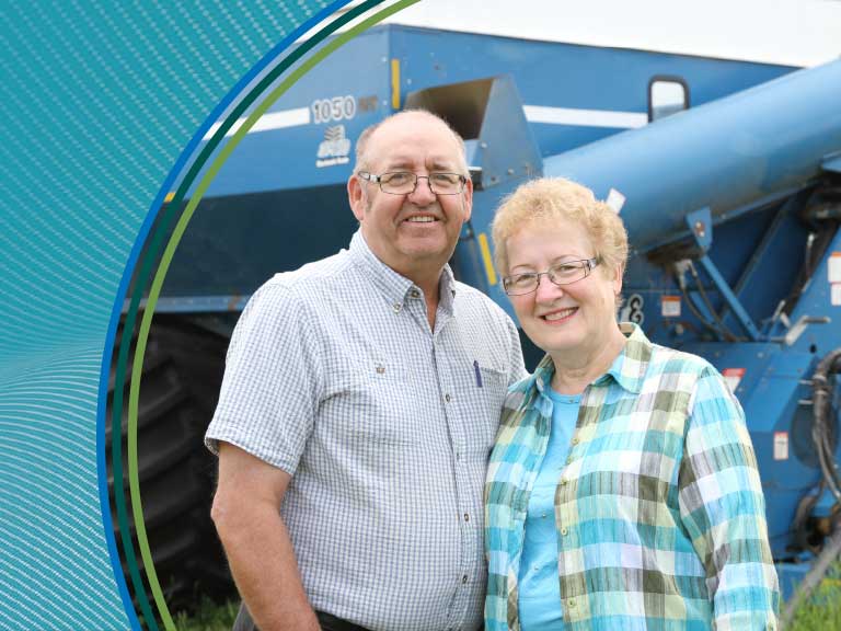 Farmers standing beside a large blue tractor on a farm in Canada.