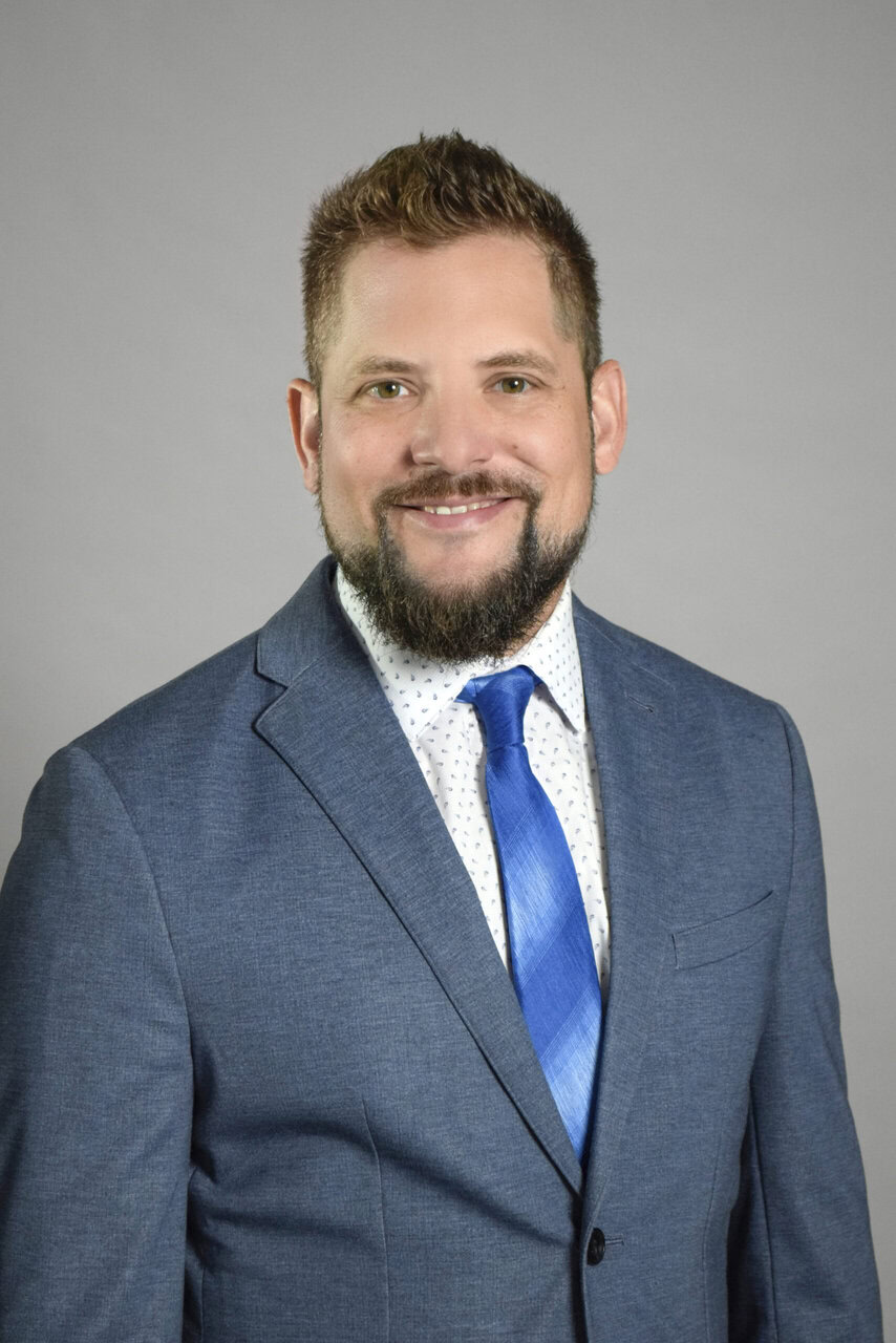 Professional man in a blue suit and tie smiling for the camera.